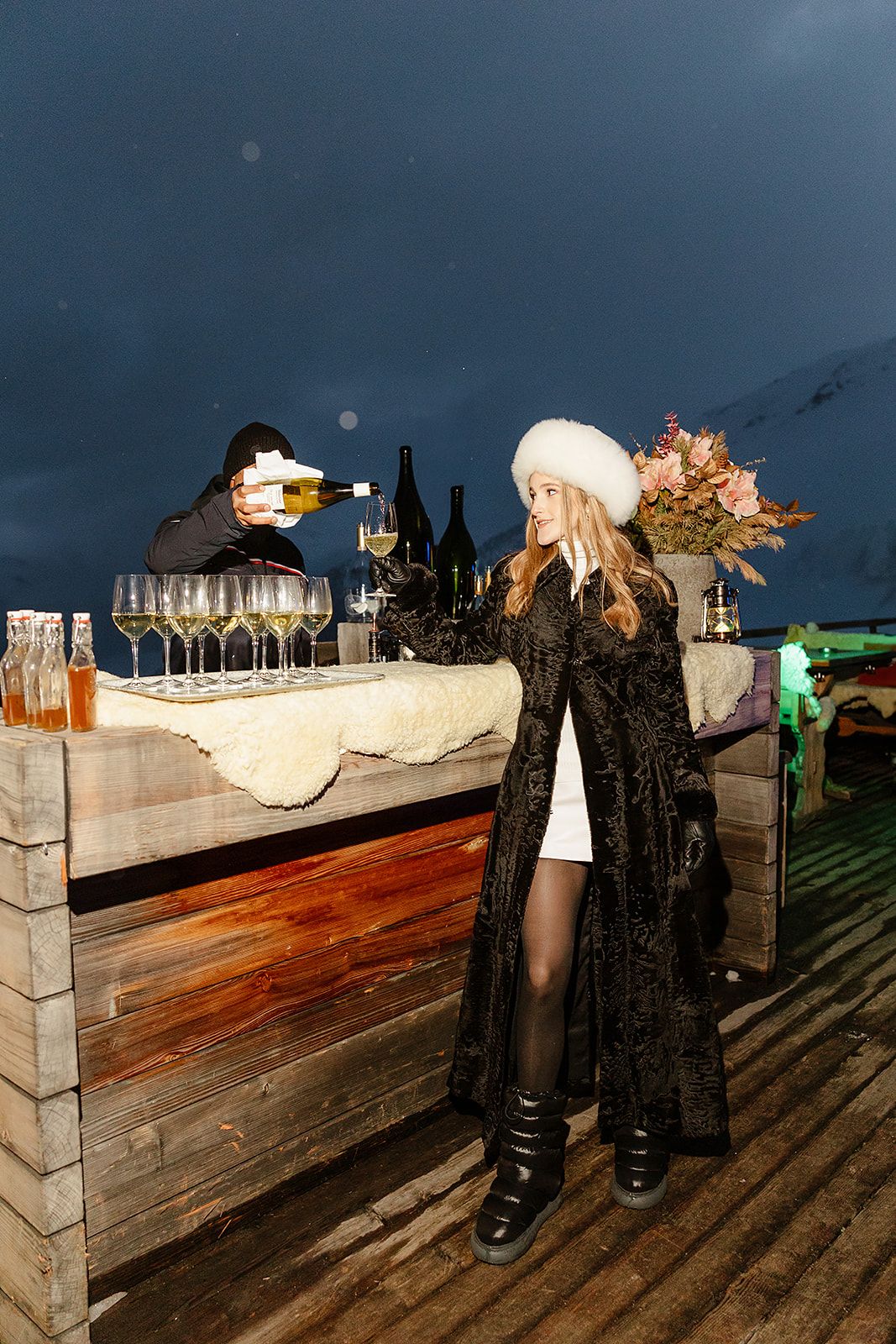 Bride with glass of wine at the welcome dinner of old world winter wedding in Saint Moritz