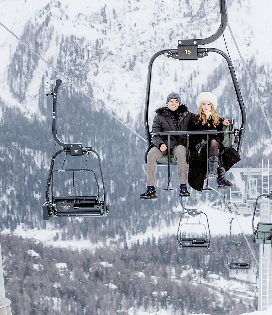 Bride and groom on chairlift to the welcome dinner of old world winter wedding in Saint Moritz