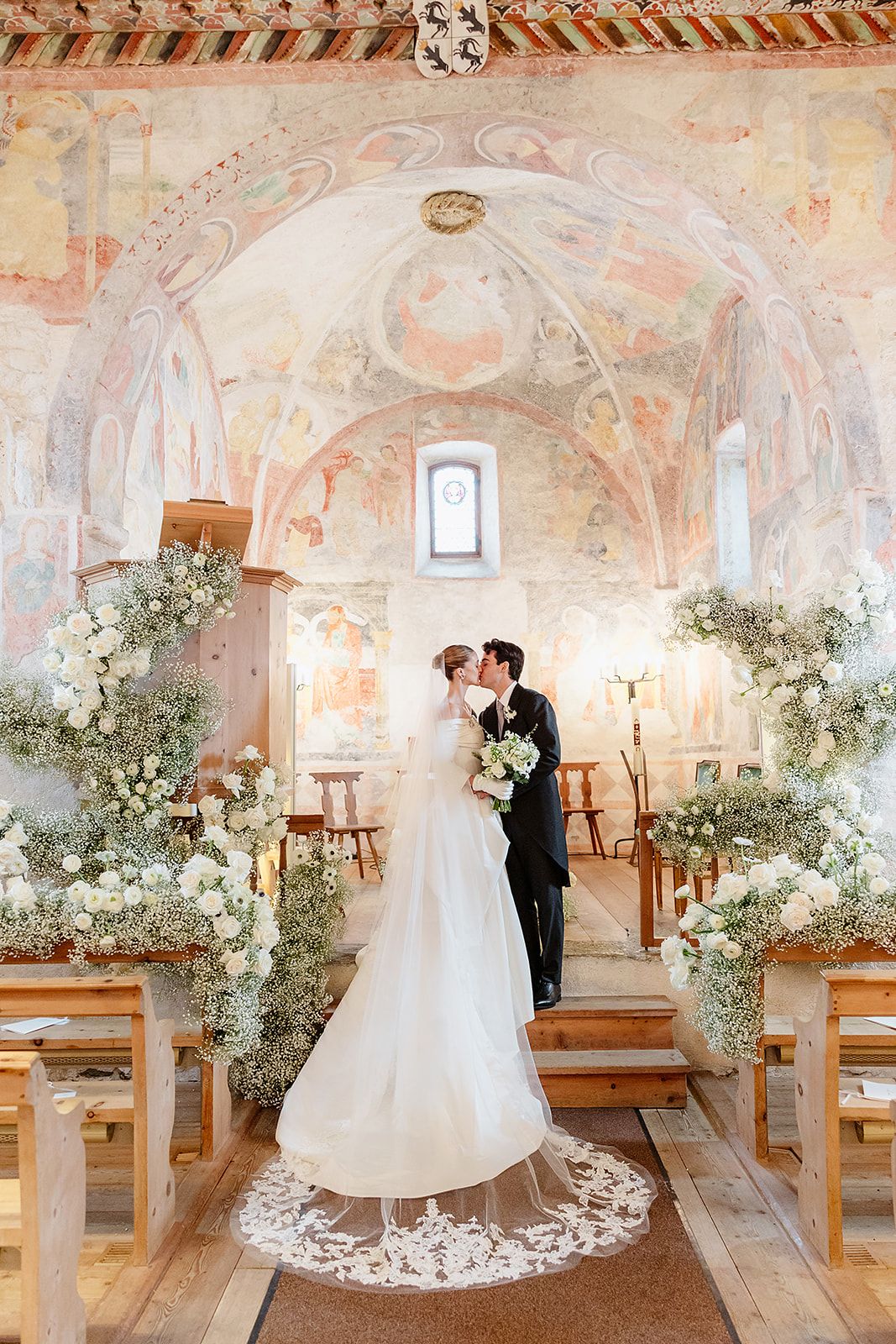 Bride and groom kiss in the church at the old world winter wedding in Saint Moritz